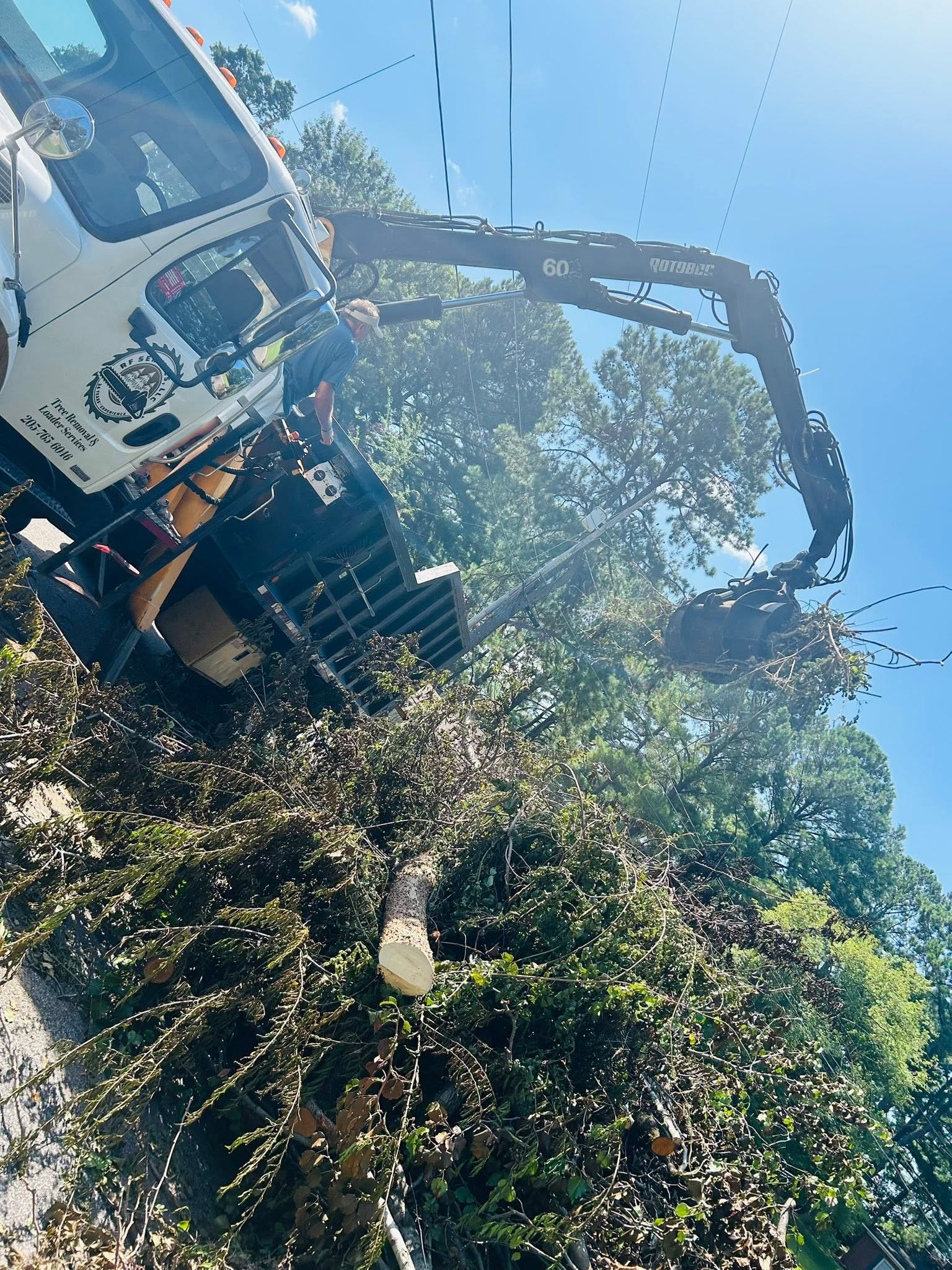RF Services loader grapple clearing storm debris near power lines